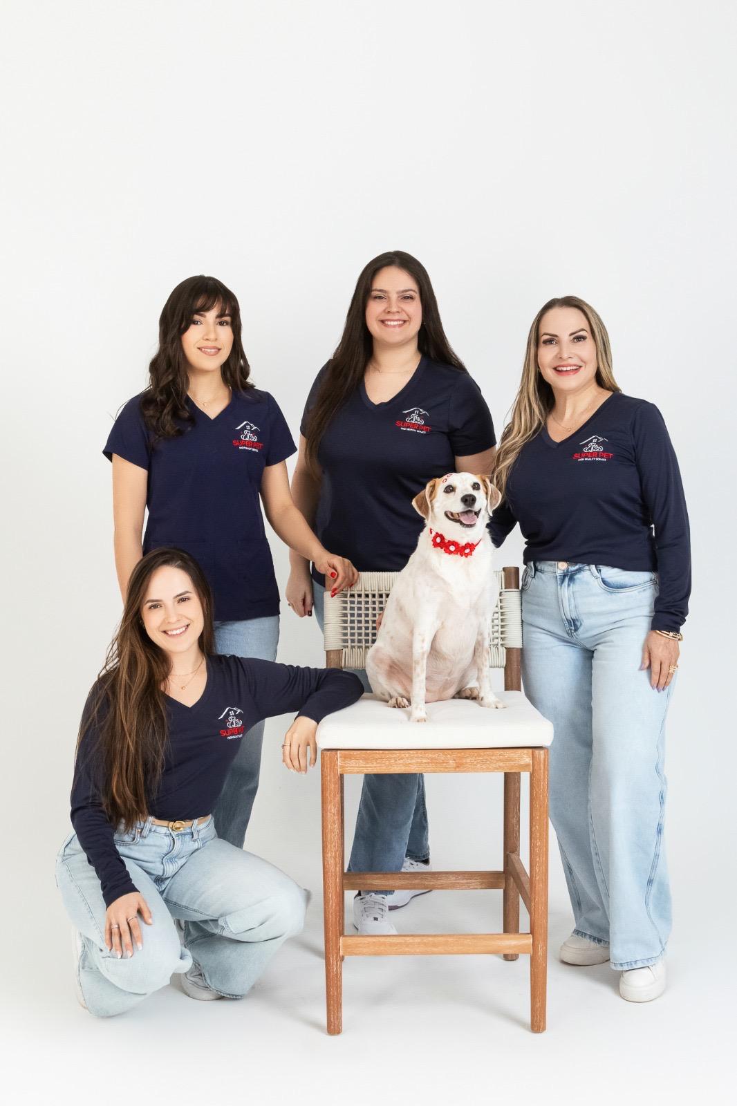 The Super Pet team — four certified groomers in navy uniforms posing with a happy dog wearing a red collar